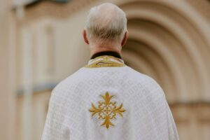 sacerdote di spalle fuori una chiesa